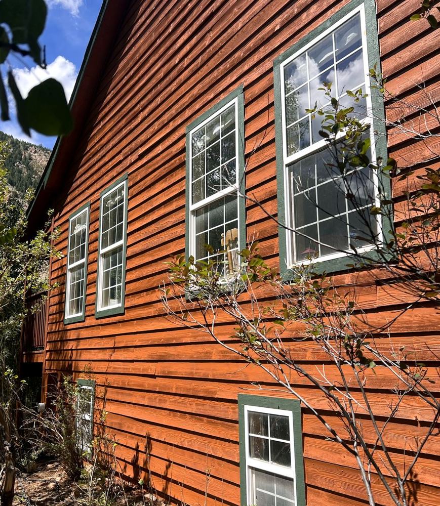 Cedar-toned siding with green window trim