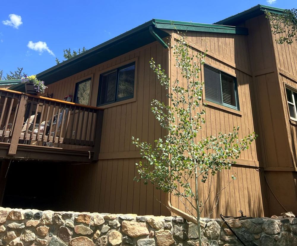 Tan board and batten home with green trim and deck